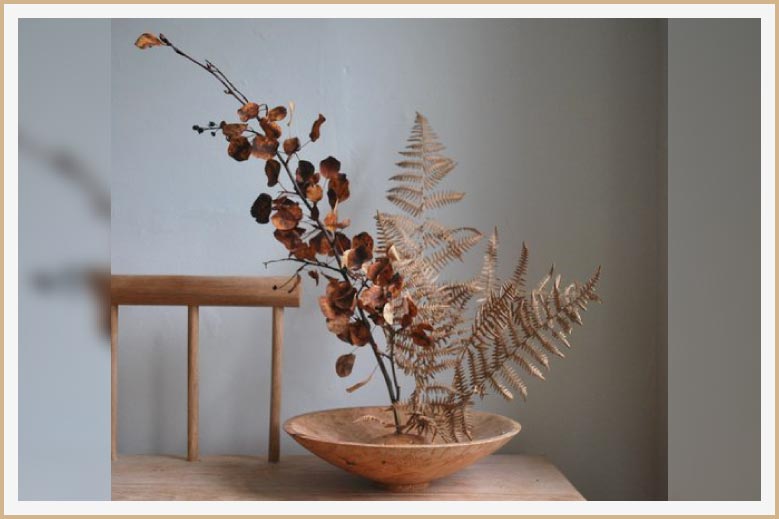 Arte floral japonés con flores secas y helechos.